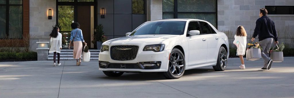 White Chrysler 300 parked in front of a busy street.
